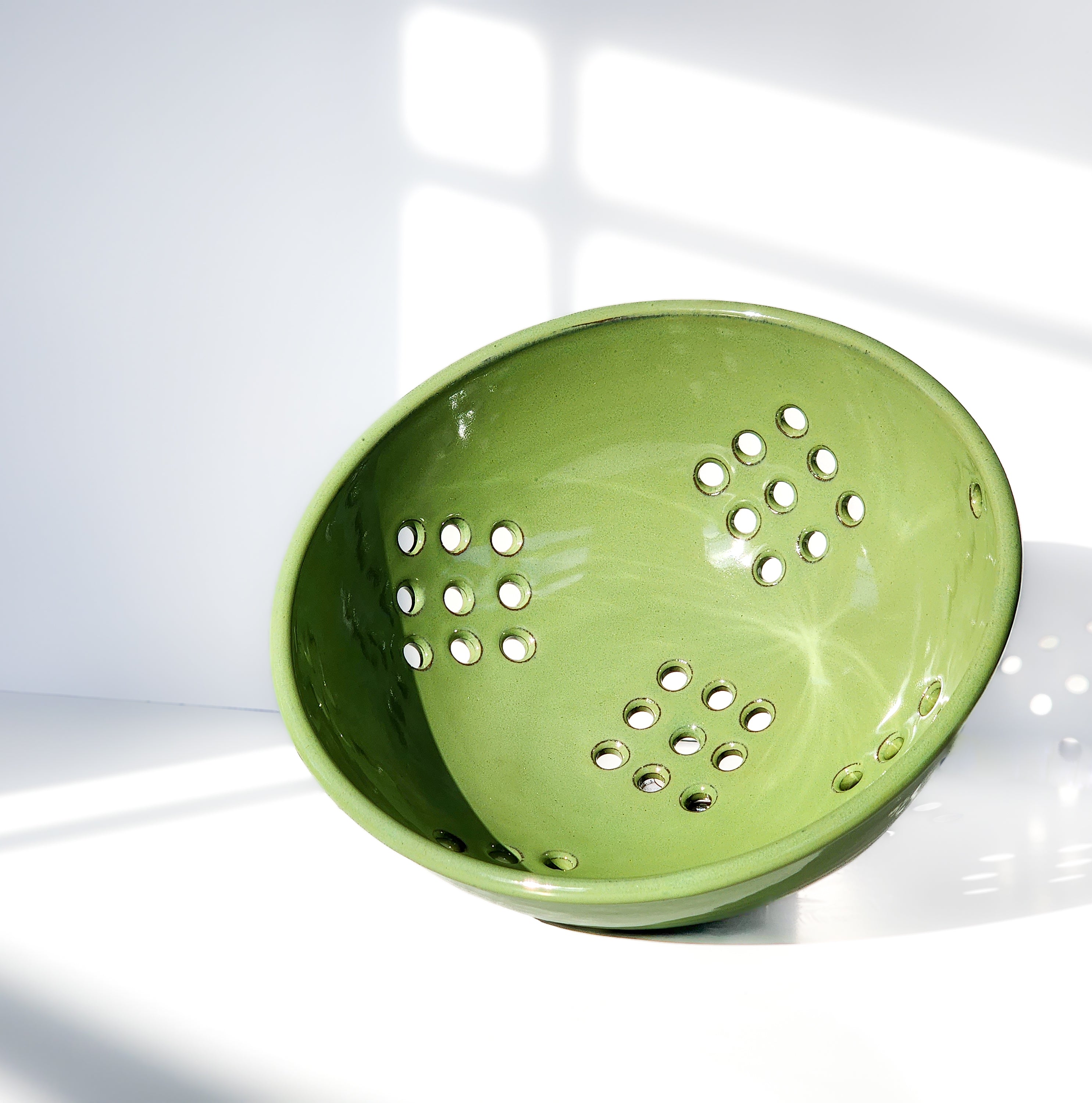 Image: Clinton Pottery's Handmade Large Colander in Bud Green – A spacious and practical 12.5 cup colander, expertly crafted. This soothing Bud Green piece in a larger size is perfect for washing larger quantities of fruits and vegetables. Expertly designed to balance functionality and style, it brings a touch of charm to your kitchen routine.