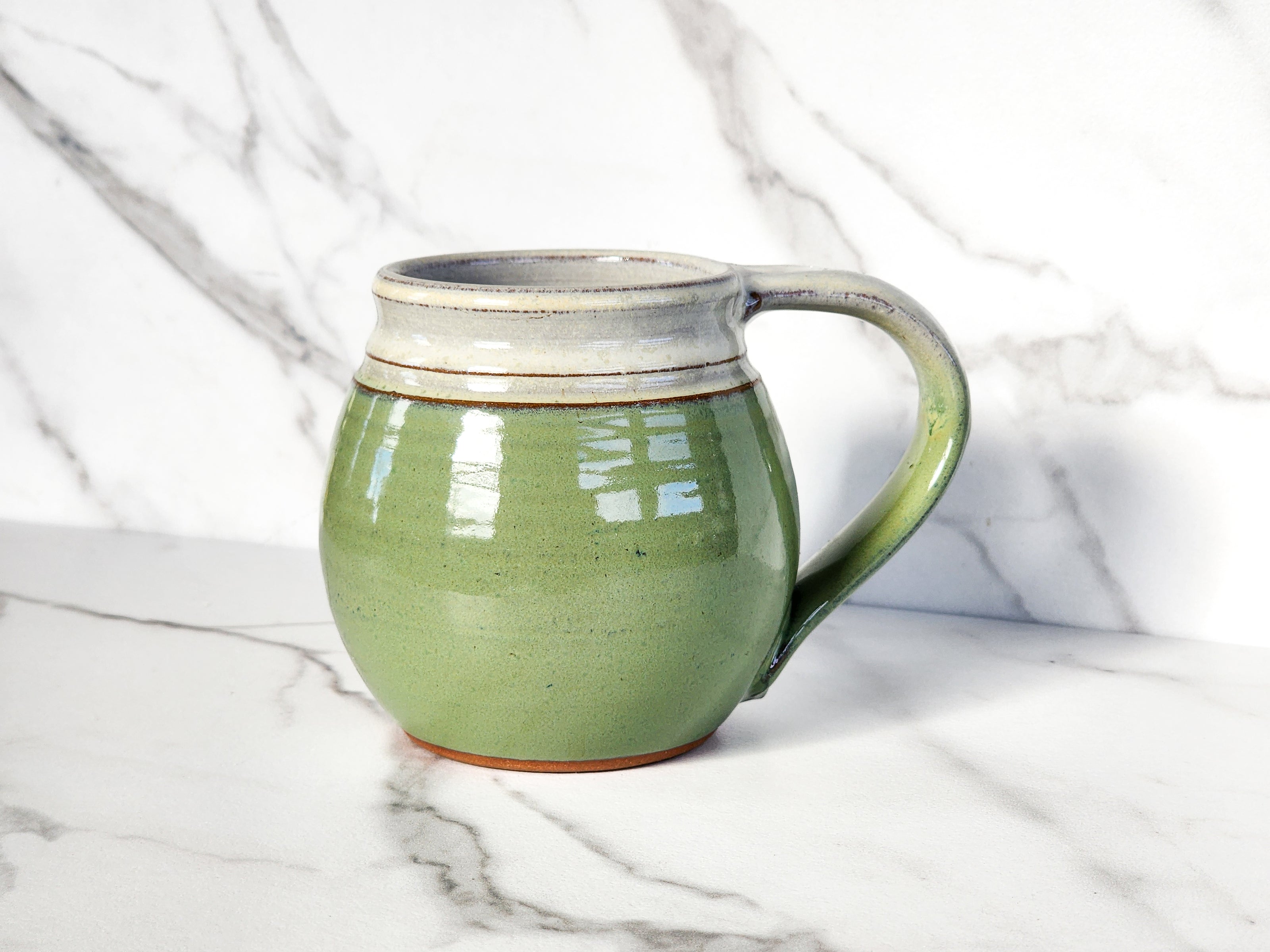Add a touch of nature to your morning routine with the Bud Green medium mug by Clinton Pottery. Crafted with care, this stylish mug is perfect for enjoying your favorite hot beverages in style.