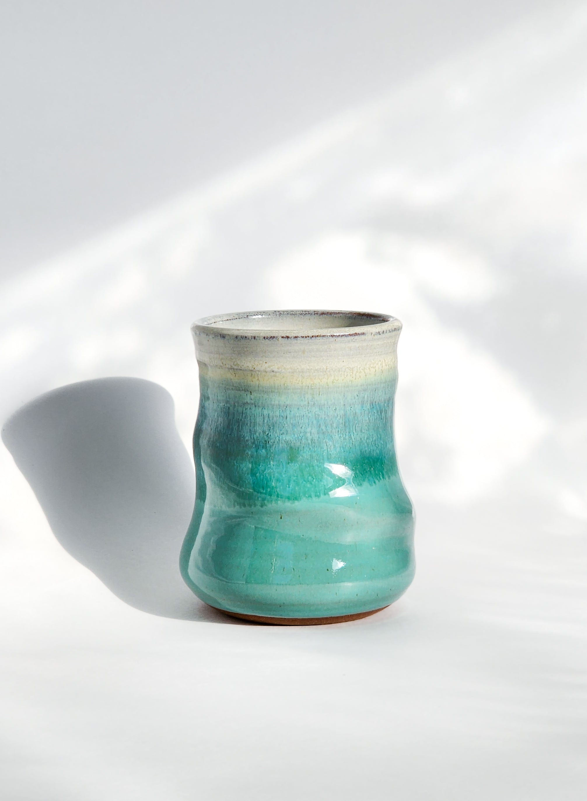 Image: Clinton Pottery's 15 oz Large Tumbler in Sky Blue – A visually striking addition with a cool, curvy design for a comfortable grip. This machine washable tumbler, crafted with care, adds contemporary elegance. The tranquil Sky Blue color brings a calming and refreshing touch, reminiscent of clear skies and tranquil waters.