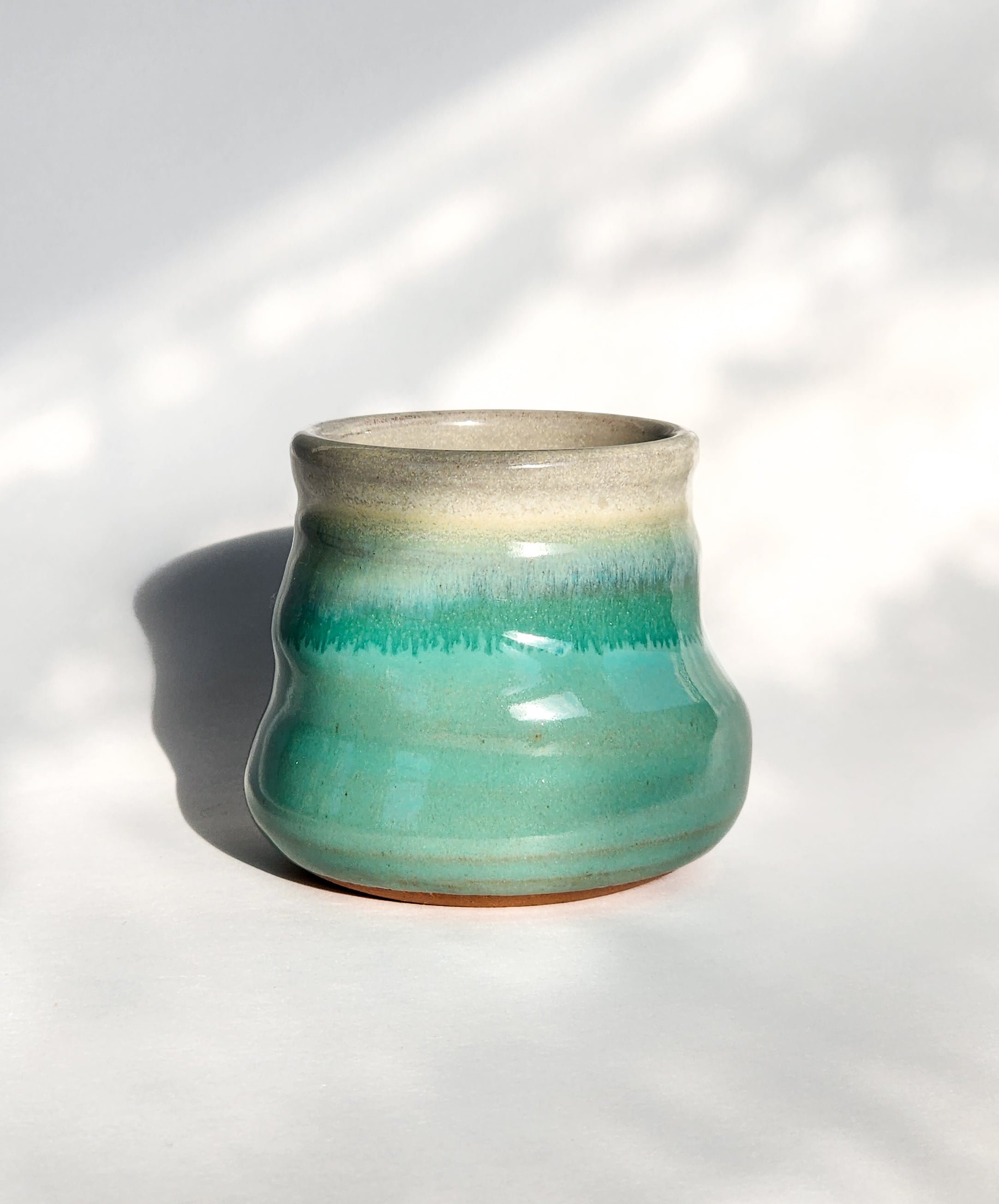 Image: Clinton Pottery's 8 oz Small Tumbler in Sky Blue – A visually appealing addition with a cool, curvy design for a comfortable grip. This machine washable tumbler, crafted with care, adds contemporary elegance. The tranquil Sky Blue color brings a calming and refreshing touch, reminiscent of clear skies and tranquil waters.