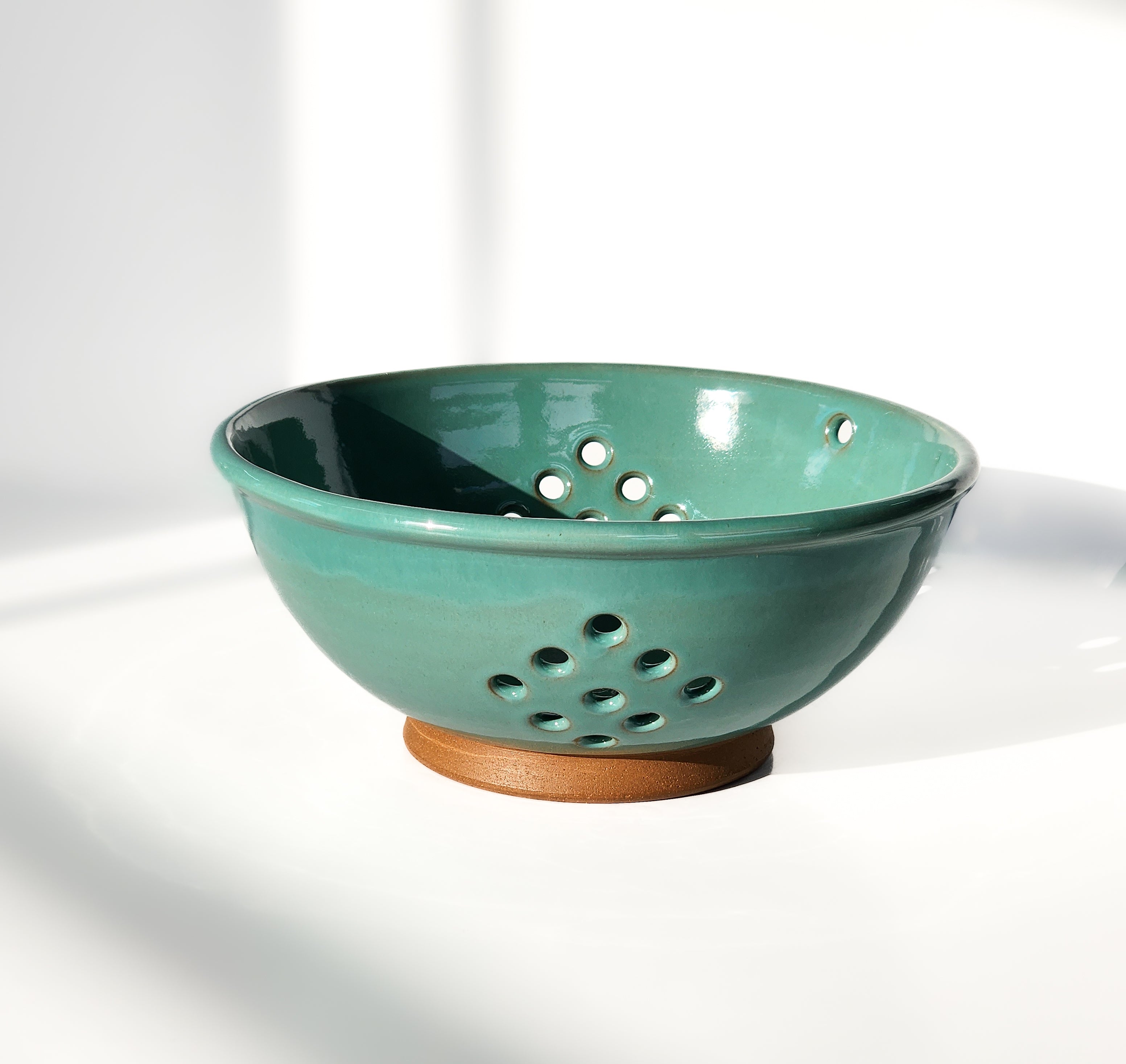 Image: Clinton Pottery's Handmade Large Colander in Sky Blue – A serene and practical 12.5 cup colander, expertly crafted. This Sky Blue piece in a larger size brings a touch of tranquility to your kitchen, perfect for washing larger quantities of fruits and vegetables. The soft blue hue evokes a sense of calmness and freshness.