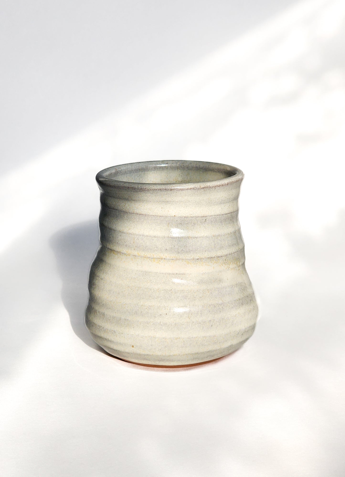 Image: Clinton Pottery's 8 oz Small Tumbler in White – A visually appealing addition with a cool, curvy design for a comfortable grip. This machine washable tumbler, crafted with care, adds contemporary elegance. The timeless White color brings a clean and versatile touch, reminiscent of simplicity and clarity.