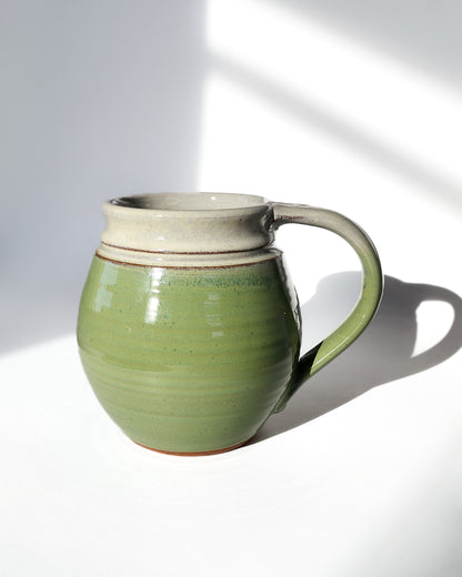 Image: Clinton Pottery's 30 oz Jumbo Mug in Bud Green – A vibrant and generously sized addition to your kitchen, this machine washable mug seamlessly blends artistry with functionality. The refreshing Bud Green color adds a touch of nature's vitality, reminiscent of spring foliage and new beginnings. Perfect for savoring generous servings of your favorite beverages with a pop of color and charm.