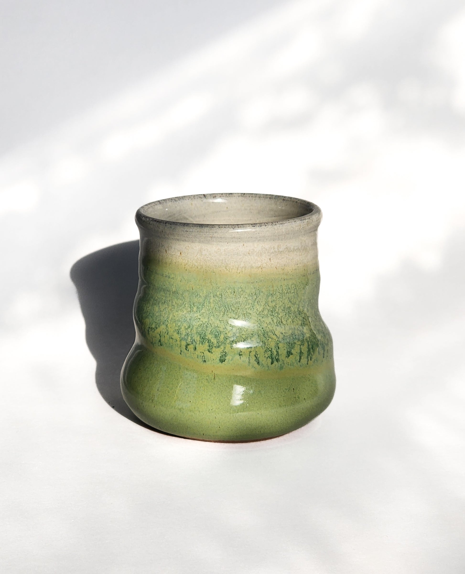 Image: Clinton Pottery's Small Tumbler in Bud Green – An 8 oz visually appealing and functional addition to your collection. This machine washable tumbler, crafted with care, features a cool, curvy design for a comfortable grip and contemporary elegance. The refreshing Bud Green color adds a touch of nature's vitality, reminiscent of spring foliage and new beginnings.