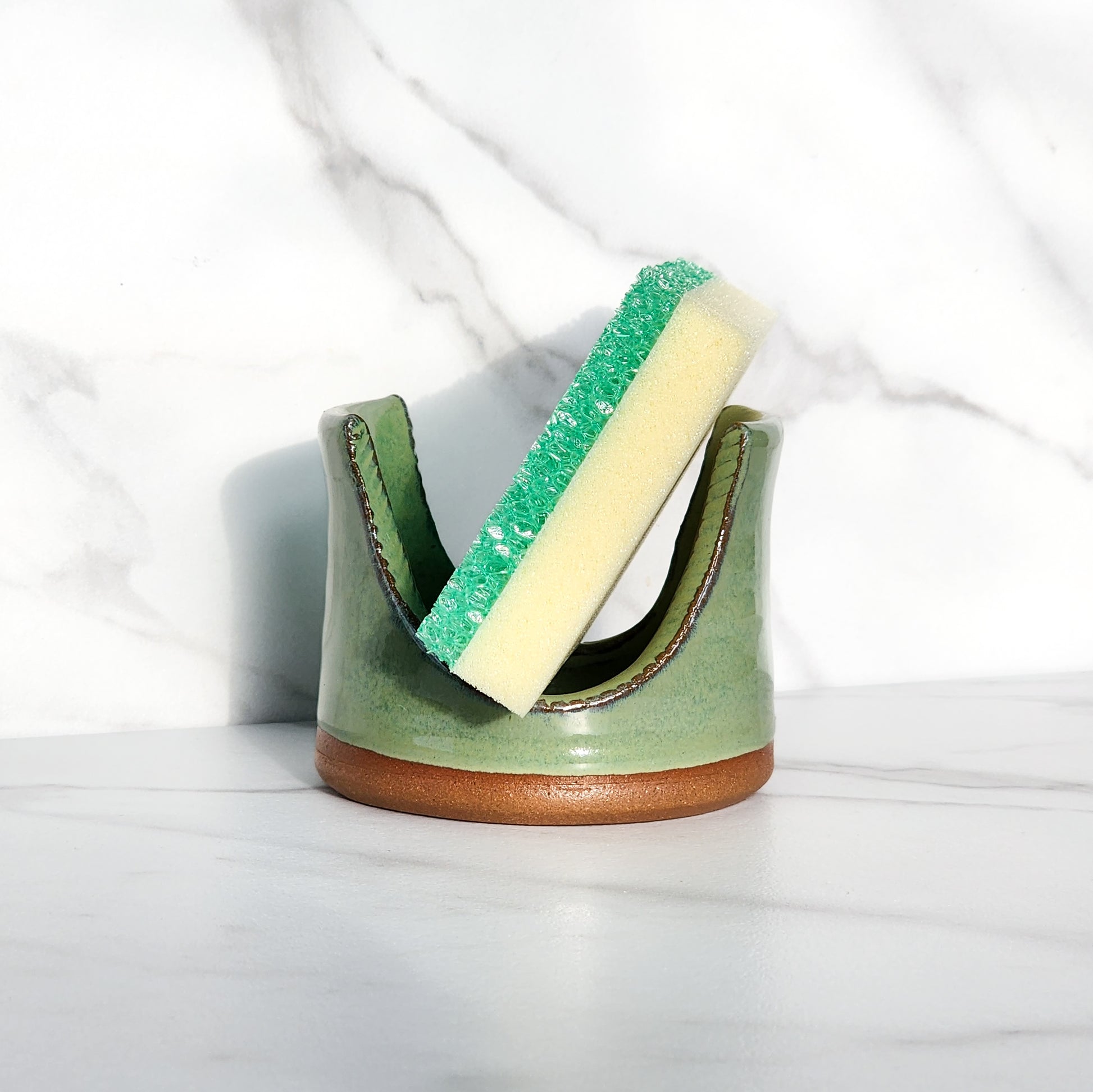 Image: Clinton Pottery's Handmade Sponge Holder in Bud Green – A visually appealing and practical kitchen accessory crafted with artisanal expertise. This durable stoneware holder in refreshing Bud Green, reminiscent of spring foliage and new growth, adds a touch of nature's vitality to your kitchen. Designed to hold your sponge securely and prevent water from spreading, it keeps your counters and sink area tidy.