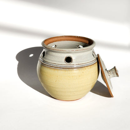 Image: A butter yellow ceramic garlic keeper, perfect for storing garlic bulbs and preserving their flavor.
