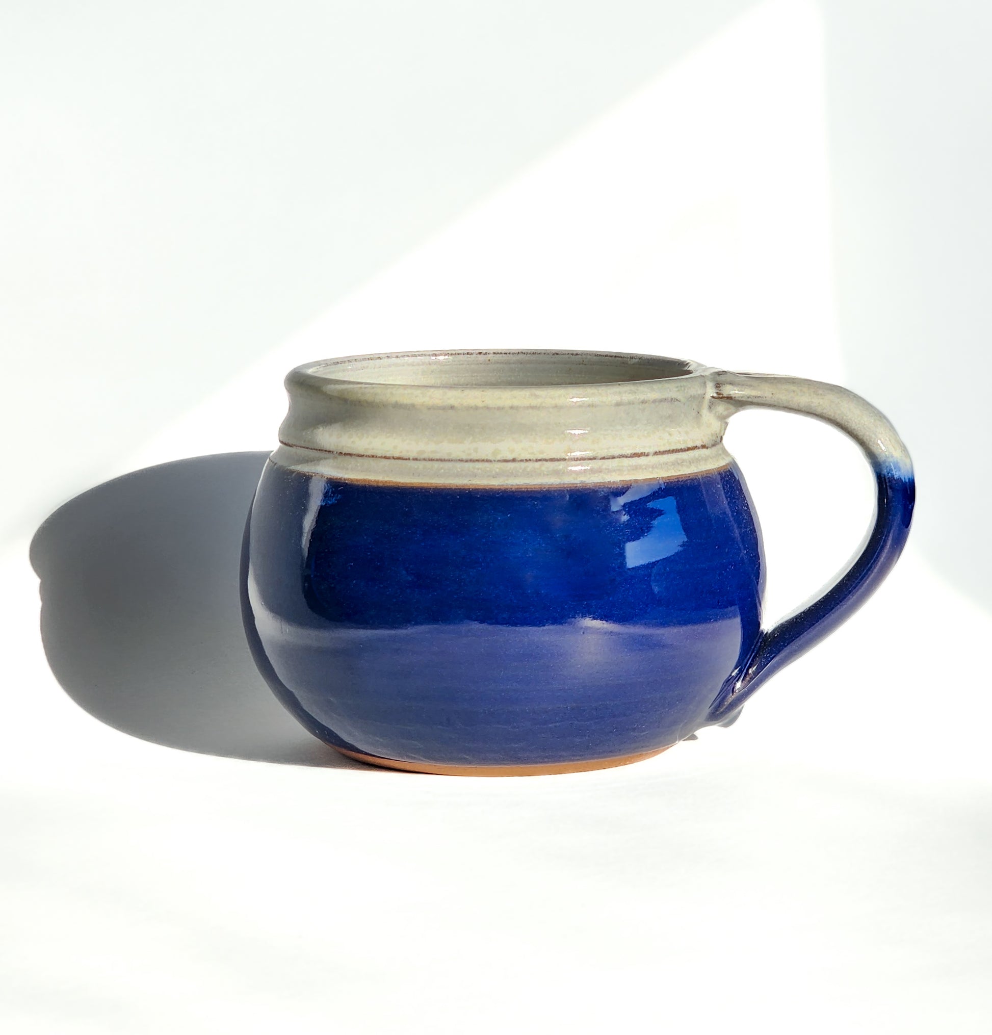 Image: Clinton Pottery's 24 oz Cereal/Soup Mug in Cobalt Blue – A bold and sophisticated choice for your kitchen, this machine washable mug seamlessly blends artistry with functionality. The deep Cobalt Blue color adds a touch of richness, reminiscent of clear skies and ocean depths. Perfect for enjoying your favorite cereal or soup, bringing a pop of timeless elegance to your dining experience.