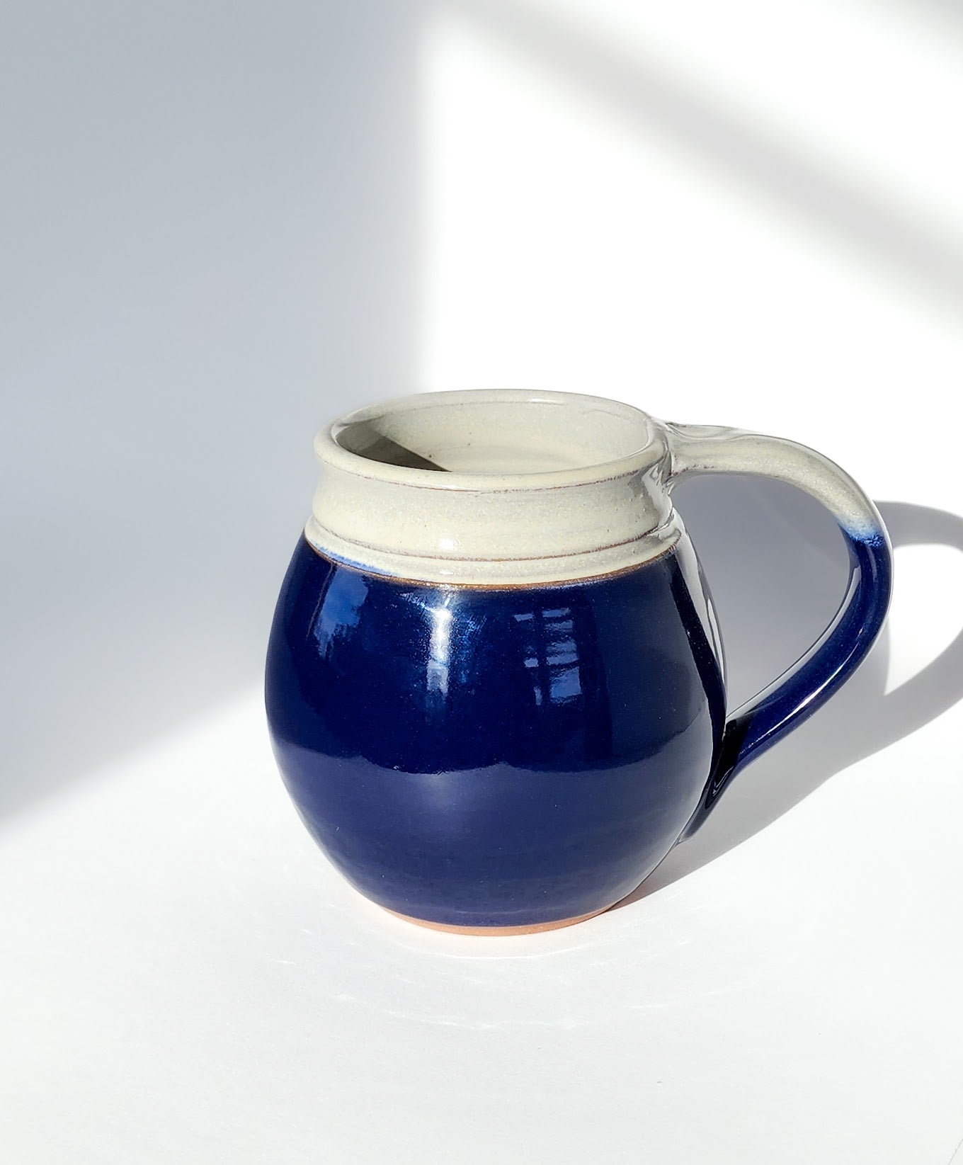 Image: Clinton Pottery's 30 oz Jumbo Mug in Cobalt – A bold and generously sized addition to your kitchen, this machine washable mug seamlessly blends artistry with functionality. The deep Cobalt color adds a touch of richness, reminiscent of clear skies and ocean depths. Perfect for enjoying ample servings of your favorite coffee or tea with a pop of timeless elegance.
