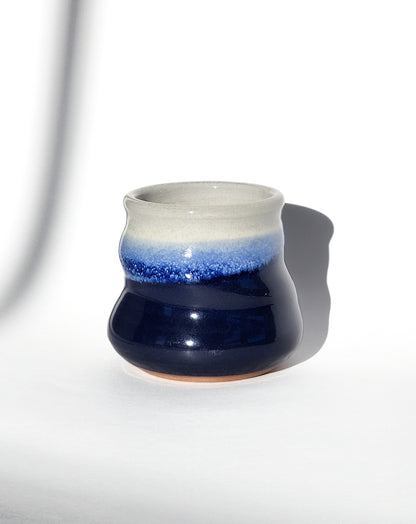 Image: Clinton Pottery's 8 oz Small Tumbler in Cobalt Blue – A visually appealing addition with a cool, curvy design for a comfortable grip. This machine washable tumbler, crafted with care, adds contemporary elegance. The deep Cobalt Blue color brings richness, reminiscent of clear skies and ocean depths.