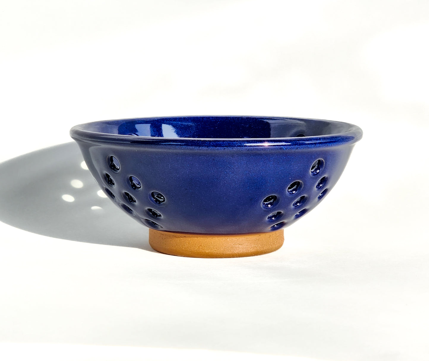  Image: Clinton Pottery's Handmade Small Colander in Cobalt – A bold and practical 2.25 cup colander, expertly crafted. This deep Cobalt piece adds a touch of sophistication to your kitchen, reminiscent of serene waters and timeless elegance. Ideal for washing berries and smaller items, it seamlessly combines style with functionality