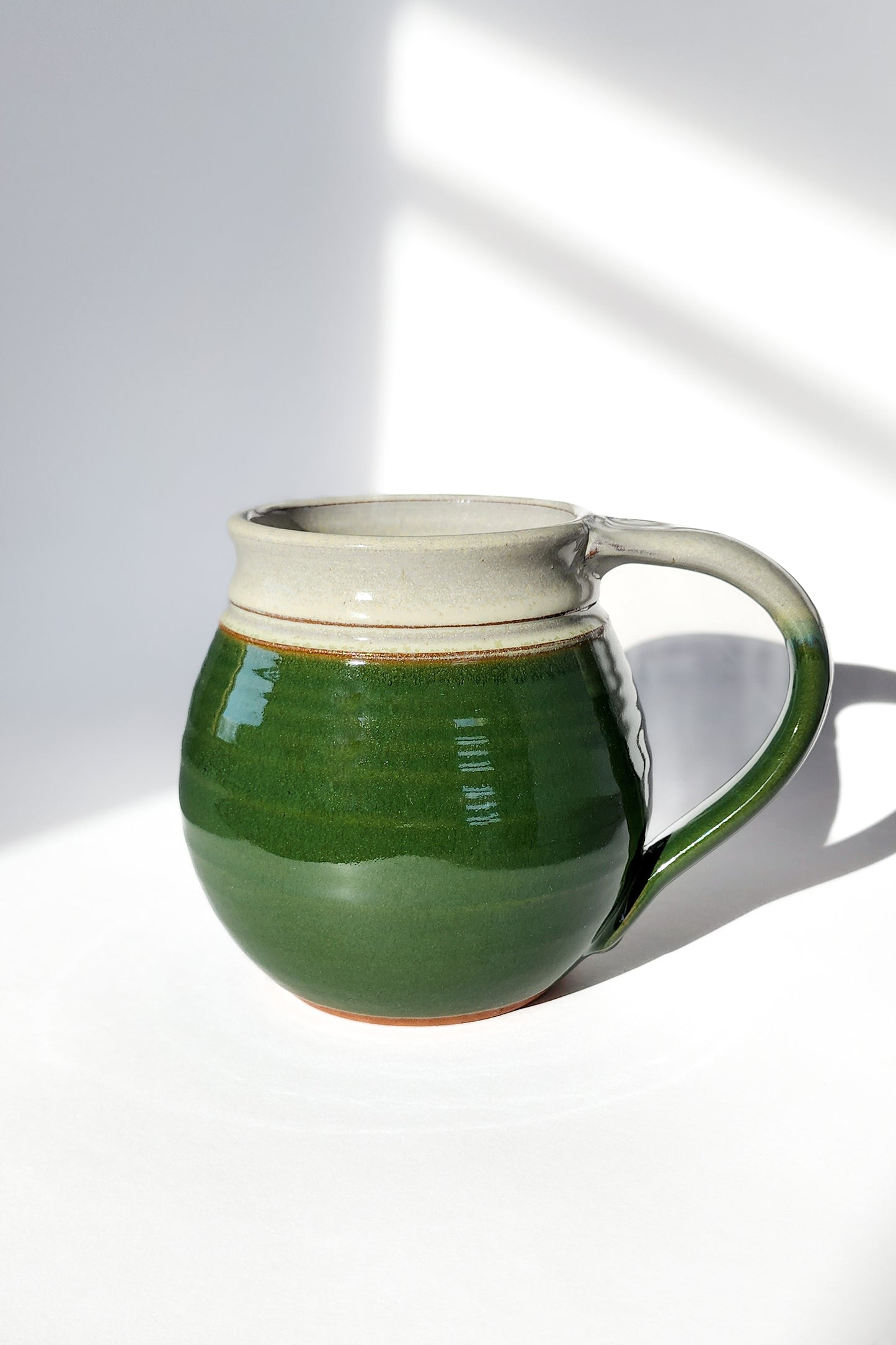 Image: Clinton Pottery's 30 oz Jumbo Mug in Dark Green – A serene and generously sized addition to your kitchen, this machine washable mug seamlessly blends artistry with functionality. The deep Dark Green color adds a touch of tranquility, reminiscent of lush forests and nature's beauty. Perfect for enjoying ample servings of your favorite coffee or tea with a hint of natural elegance.