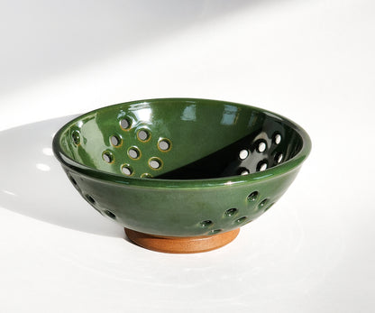 Image: Clinton Pottery's Handmade Medium Colander in Dark Green – A rich and functional kitchen accessory, expertly crafted. This 4 cup colander in deep Dark Green brings the tranquility of lush forests and the elegance of nature to your kitchen. Perfect for washing fruits, veggies, or as a stylish counter fruit bowl, its machine washable design seamlessly blends functionality with the captivating allure of Dark Green. Ideal for those seeking style and practicality with a touch of natural sophistication.