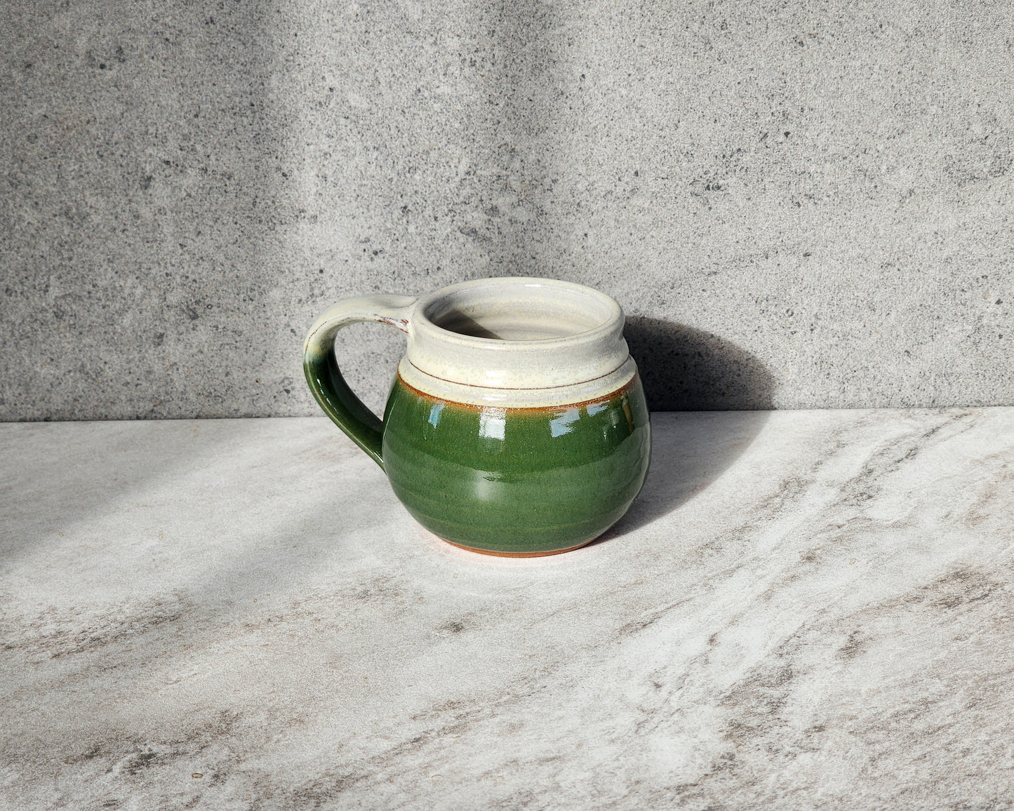 Indulge in the rustic charm of the Dark Green small mug by Clinton Pottery. With its deep, earthy tone reminiscent of lush forests, this mug brings a sense of tranquility to your coffee or tea time. Crafted with care and designed for comfort, it's the perfect vessel for enjoying your favorite hot beverage. 