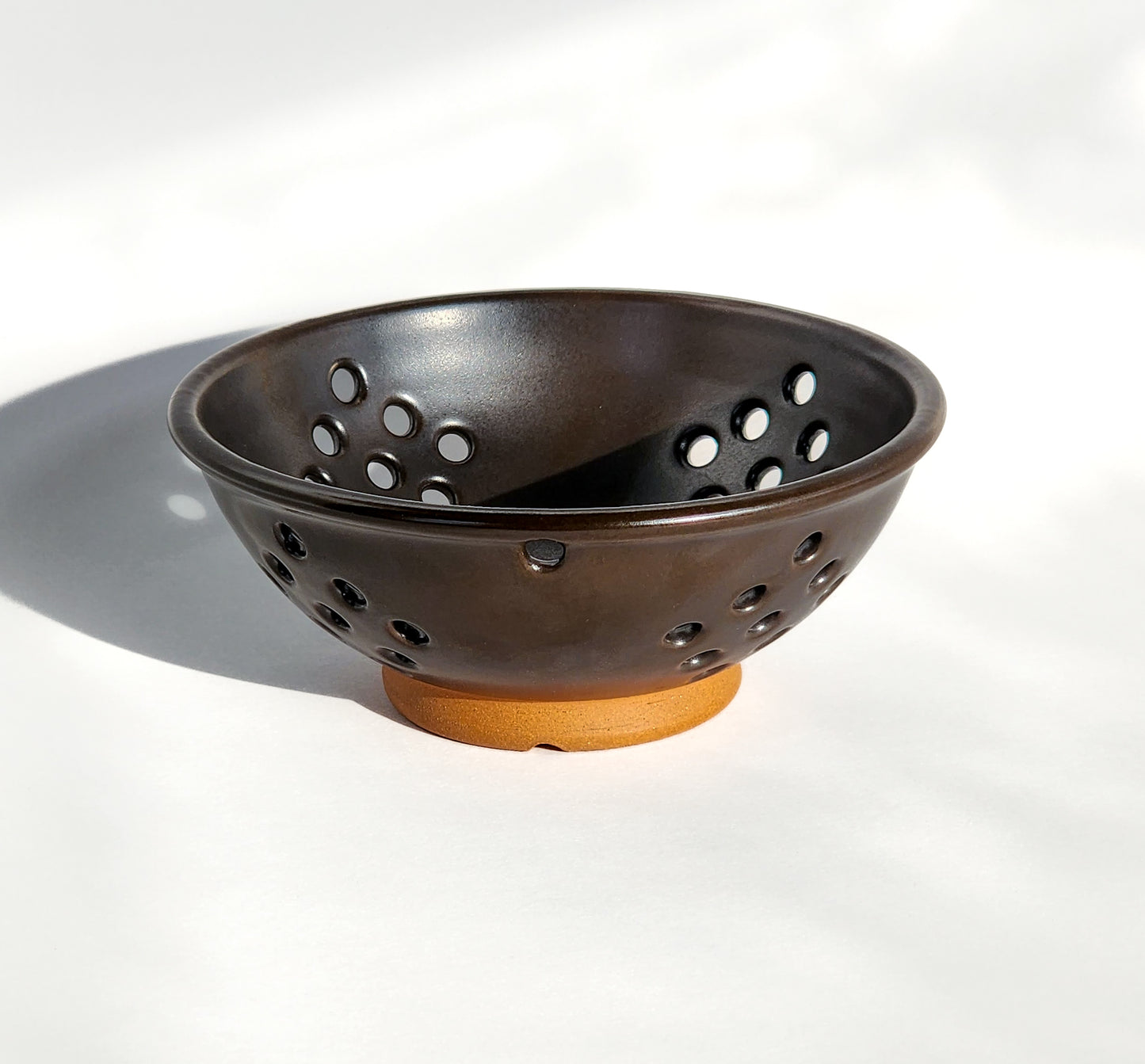  Image: Clinton Pottery's Handmade Small Colander in Licorice – A sleek and practical 2.25 cup colander, expertly crafted. This Licorice Black piece adds a touch of modern sophistication to your kitchen, reminiscent of refined simplicity and timeless style. Ideal for washing berries and smaller items, it seamlessly combines style with functionality.