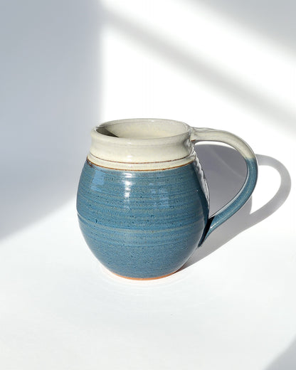 Image: Clinton Pottery's 30 oz Jumbo Mug in Light Blue – A calming and generously sized addition to your kitchen, this machine washable mug seamlessly blends artistry with functionality. The soothing Light Blue color adds a touch of tranquility, reminiscent of clear skies and coastal horizons. Perfect for enjoying ample servings of your favorite coffee or tea with a breath of peaceful elegance.