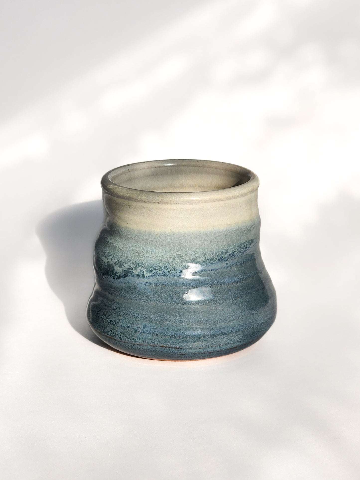 Image: Clinton Pottery's 8 oz Small Tumbler in Light Blue – A visually appealing addition with a cool, curvy design for a comfortable grip. This machine washable tumbler, crafted with care, adds contemporary elegance. The serene Light Blue color brings a calming and refreshing touch, reminiscent of clear skies and tranquil waters.