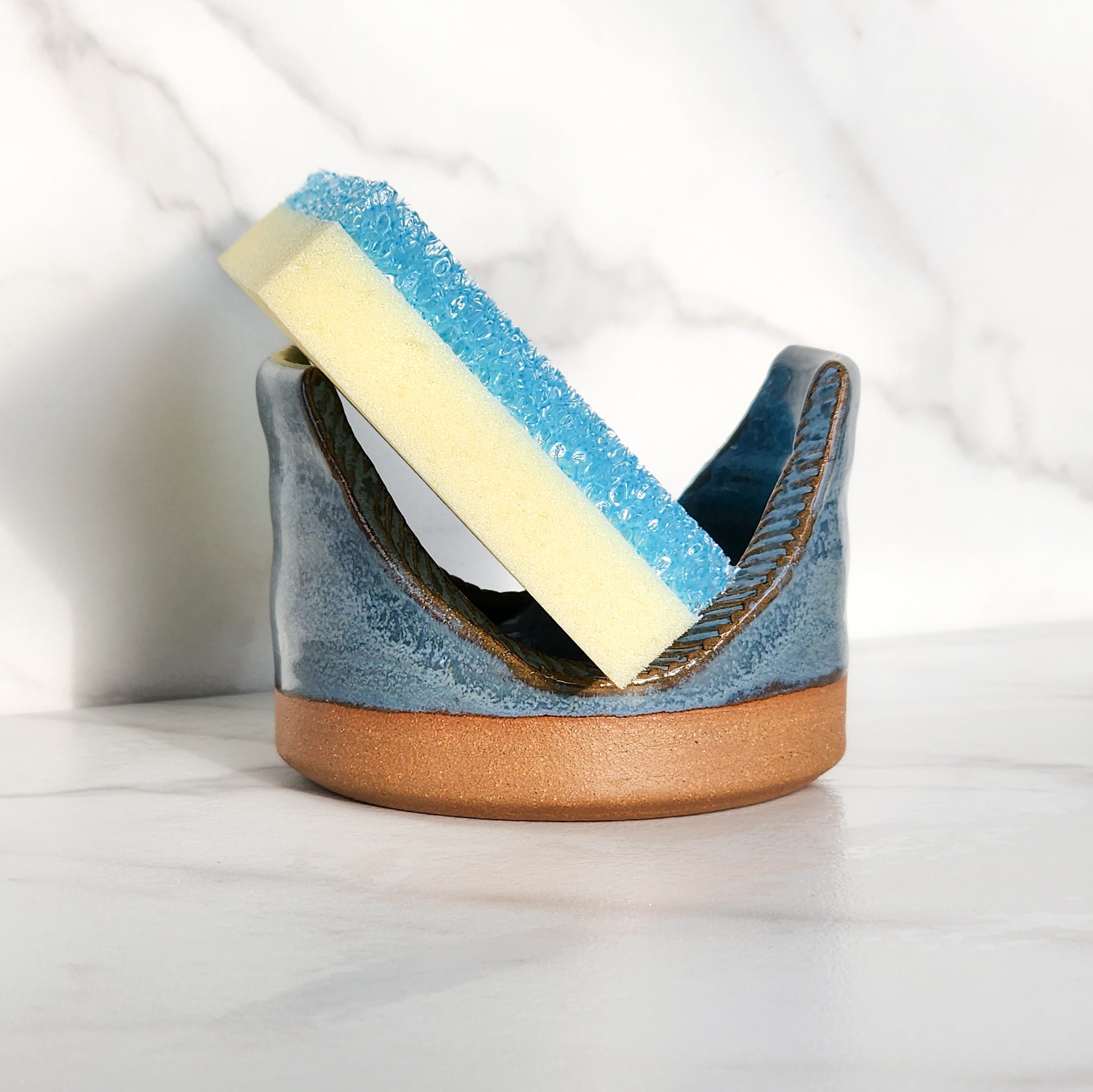  Image: Clinton Pottery's Handmade Sponge Holder in Light Blue – A refreshing and practical kitchen accessory, thoughtfully crafted by artisans. This durable stoneware holder, in serene Light Blue, adds a touch of tranquility to your kitchen, reminiscent of clear skies and calm waters. Designed to securely hold your sponge and prevent water spread, it keeps your counters and sink area tidy.