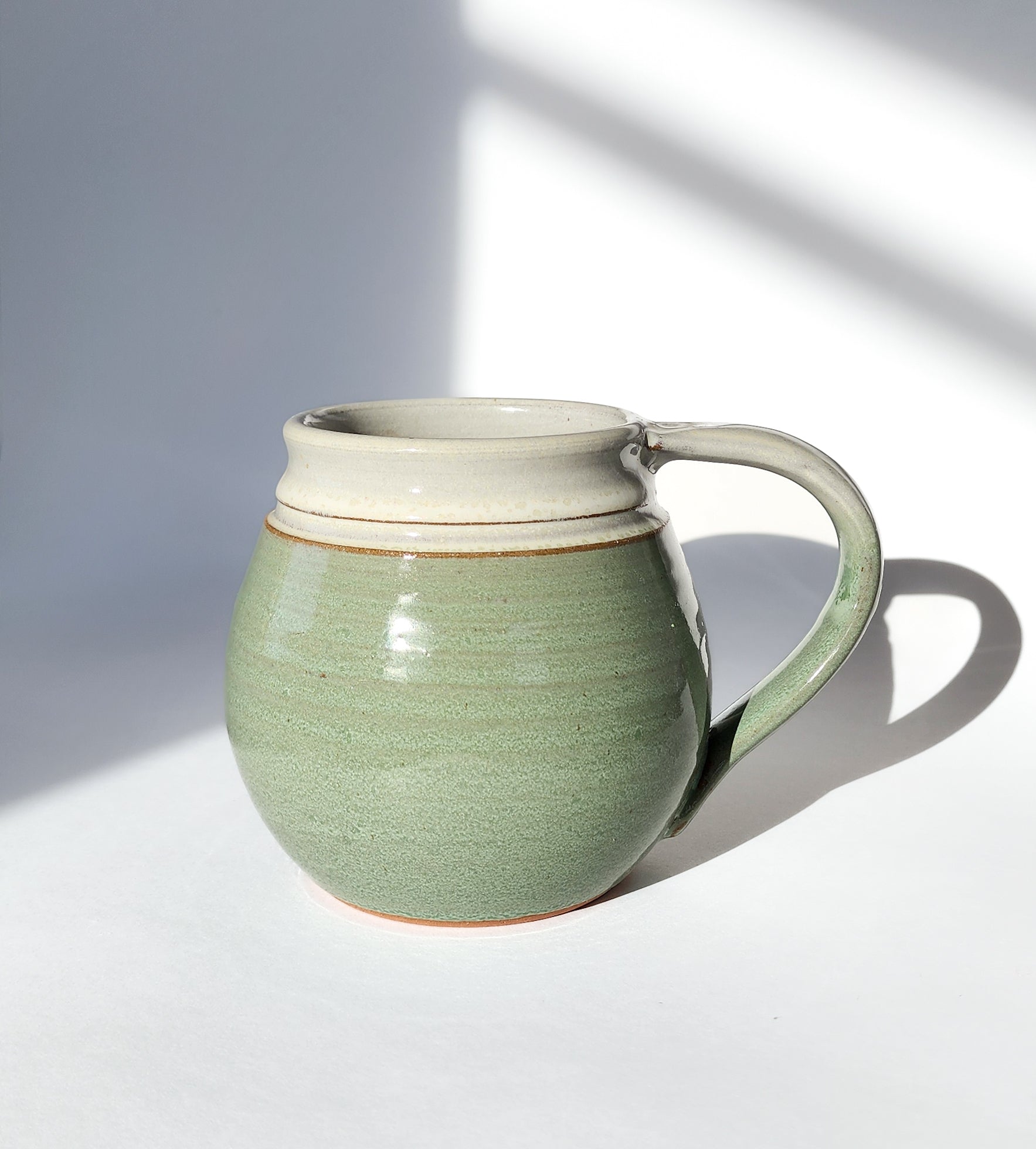 Image: Clinton Pottery's 30 oz Jumbo Mug in Light Green – A fresh and generously sized addition to your kitchen, this machine washable mug seamlessly blends artistry with functionality. The invigorating Light Green color adds a touch of nature's vitality, reminiscent of spring foliage and sunlit meadows. Perfect for enjoying ample servings of your favorite coffee or tea with a breath of natural elegance.