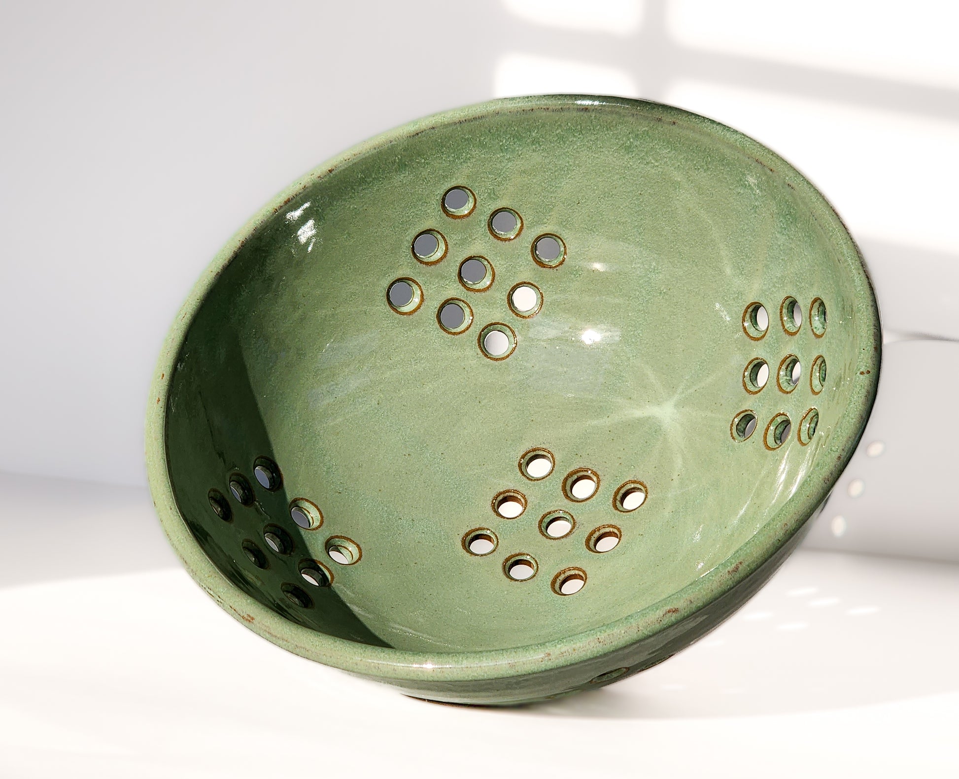 Image: Clinton Pottery's Handmade Large Colander in Light Green – A fresh and practical 12.5 cup colander, expertly crafted. This Light Green piece in a larger size is ideal for washing larger quantities of fruits and vegetables. The vibrant green hue brings a touch of nature's energy to your kitchen routine.