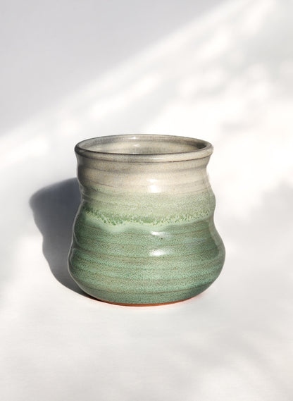 Image: Clinton Pottery's 8 oz Small Tumbler in Light Green – A visually appealing addition with a cool, curvy design for a comfortable grip. This machine washable tumbler, crafted with care, adds contemporary elegance. The invigorating Light Green color brings a touch of nature's vitality, reminiscent of spring foliage and sunlit meadows.