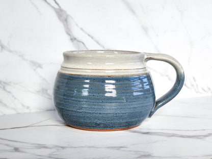  Image Description: A light blue cereal/soup bowl from Clinton Pottery sits elegantly on a table. Its smooth surface reflects the light, showcasing the soothing blue hue. The bowl's wide rim and shallow depth make it ideal for serving cereal, soup, or other delicious dishes. With its minimalist design and tranquil color, this bowl adds a touch of serenity to any mealtime.