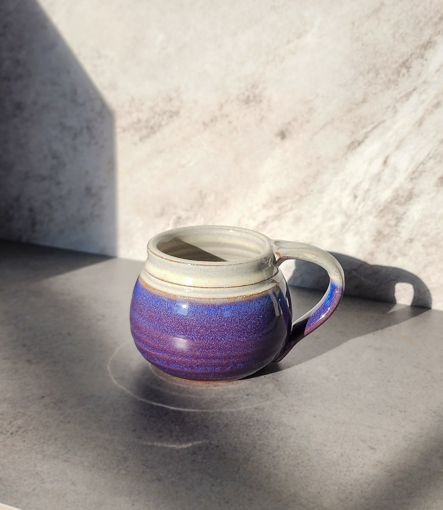 mage: Clinton Pottery's Handmade Small Mug in Purple – A vibrant and compact 10-12 oz mug, expertly crafted. This Purple piece adds a touch of regal elegance to your daily beverage routine, reminiscent of royal robes and sophistication. Ideal for savoring smaller quantities of your favorite drinks, it seamlessly combines bold style with practicality. The rich purple hue enhances the luxurious appeal of this small-sized mug. 