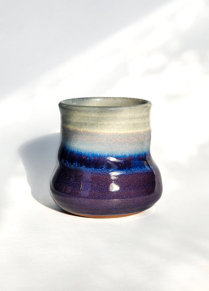 Image: Clinton Pottery's 8 oz Small Tumbler in Purple – A visually appealing addition with a cool, curvy design for a comfortable grip. This machine washable tumbler, crafted with care, adds contemporary elegance. The regal Purple color brings a touch of sophistication, reminiscent of royal richness and artistic flair.