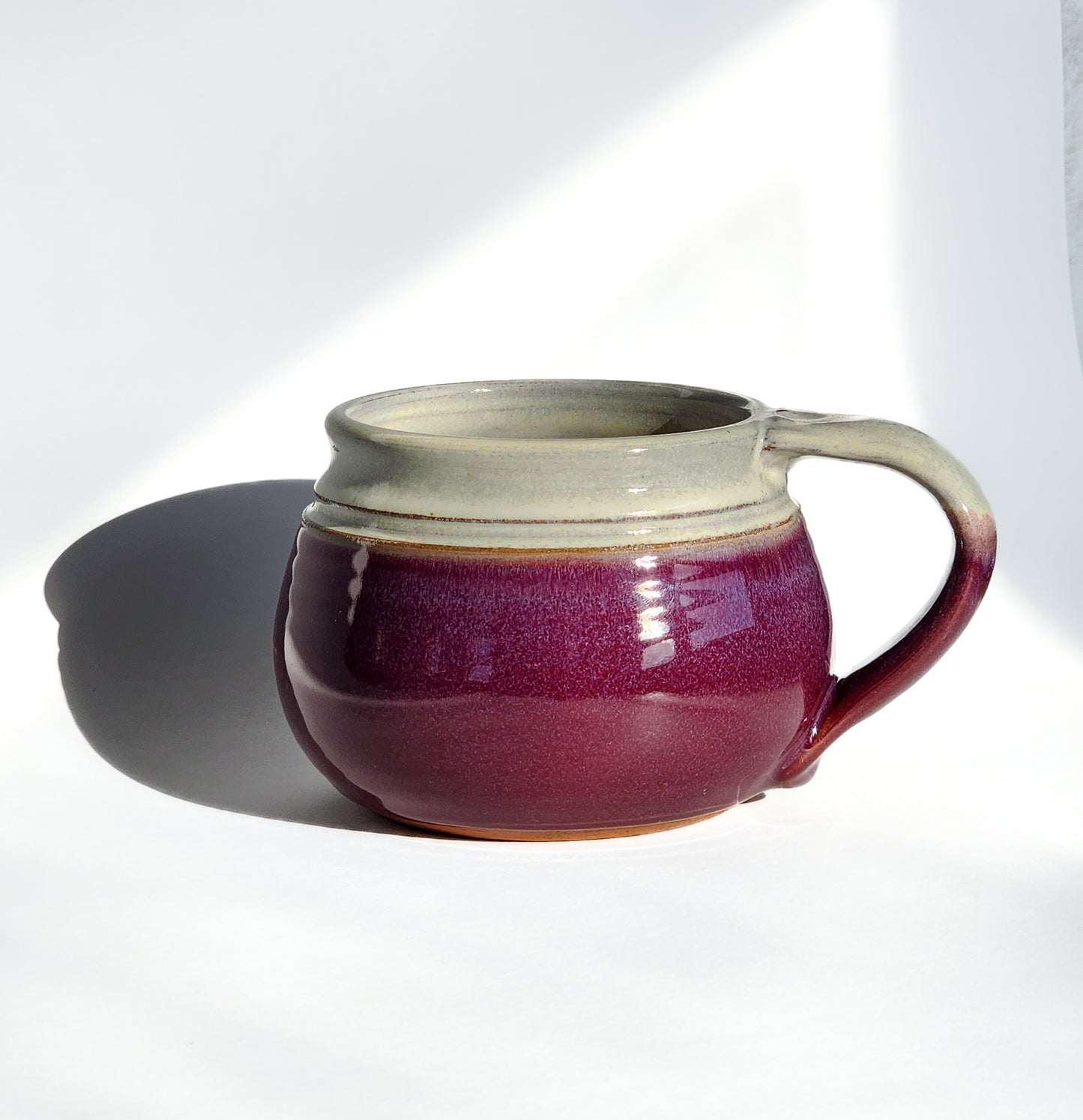 Image: Clinton Pottery's 24 oz Cereal/Soup Mug in Red/Magenta – A vibrant and captivating addition to your kitchen, this machine washable mug seamlessly blends artistry with functionality. The striking Red/Magenta color adds a burst of energy, reminiscent of ripe fruits and passionate hues. Perfect for enjoying your favorite cereal or soup, bringing a pop of bold elegance to your dining experience.