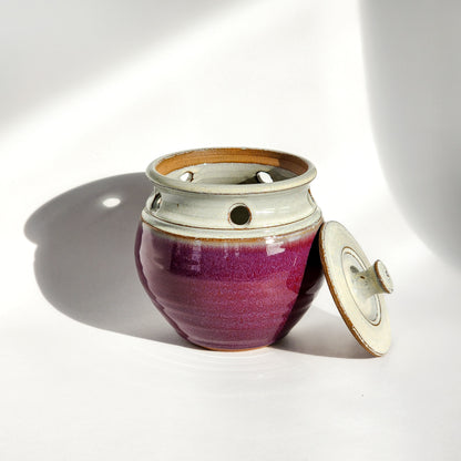 Image: A vibrant red ceramic garlic keeper, designed to store garlic bulbs and make a bold statement in the kitchen.
