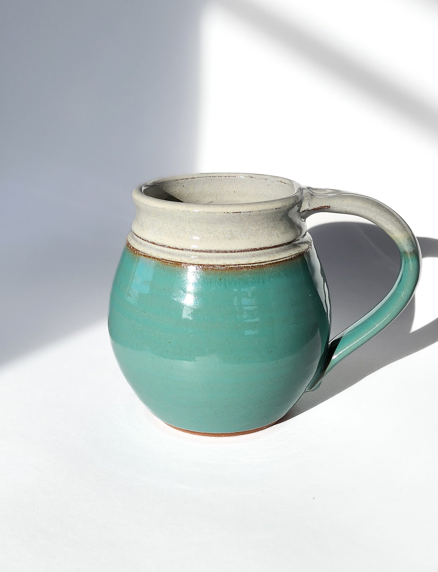 Image: Clinton Pottery's 30 oz Jumbo Mug in Sky Blue – A serene and generously sized addition to your kitchen, this machine washable mug seamlessly blends artistry with functionality. The soothing Sky Blue color adds a touch of tranquility, reminiscent of clear skies and calming waters. Perfect for enjoying ample servings of your favorite coffee or tea with a breath of peaceful charm.