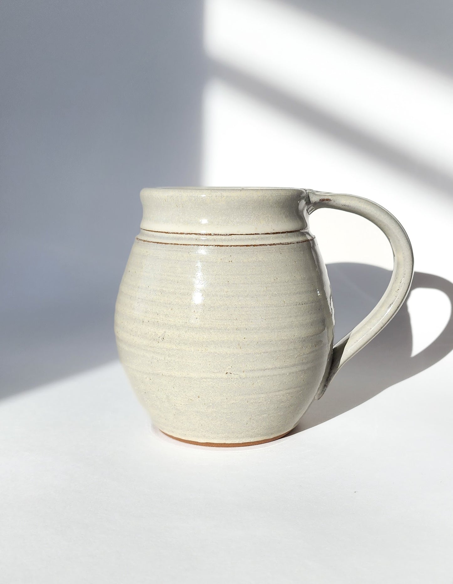 Image: Clinton Pottery's 30 oz Jumbo Mug in White – A classic and generously sized addition to your kitchen, this machine washable mug seamlessly blends artistry with functionality. The timeless White color adds a clean and versatile touch, reminiscent of simplicity and clarity. Perfect for enjoying ample servings of your favorite coffee or tea with understated elegance.
