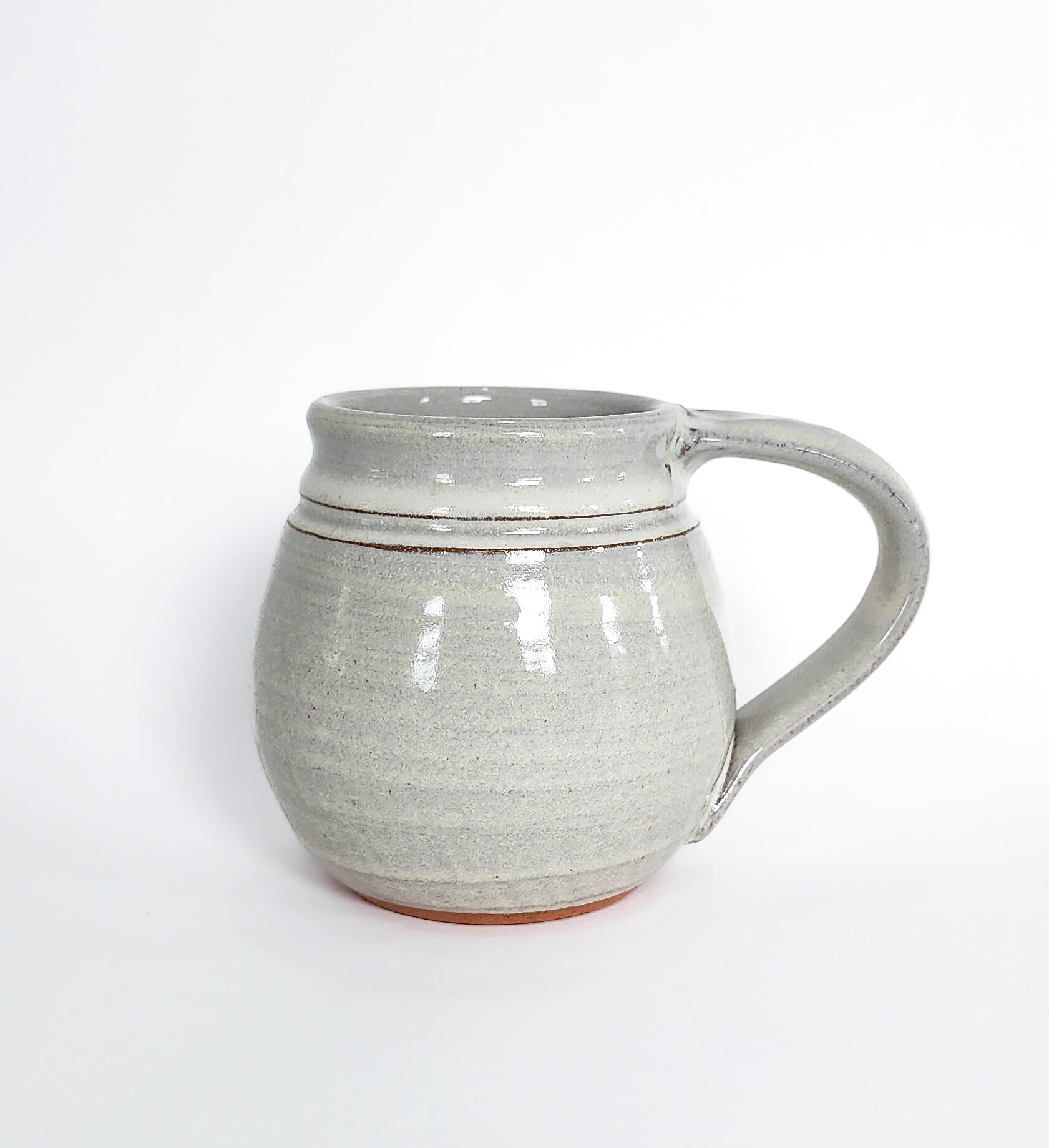 Image: Clinton Pottery's Handmade Medium Mug in White – A timeless and versatile 14-16 oz mug, expertly crafted. This White piece exudes purity and simplicity, reminiscent of fresh snowfall and clean elegance. Perfect for savoring moderate quantities of your favorite coffee or tea, it seamlessly combines classic style with functionality. 